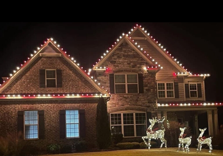 Brick and stone home with red and white lights tracing its stacked gables