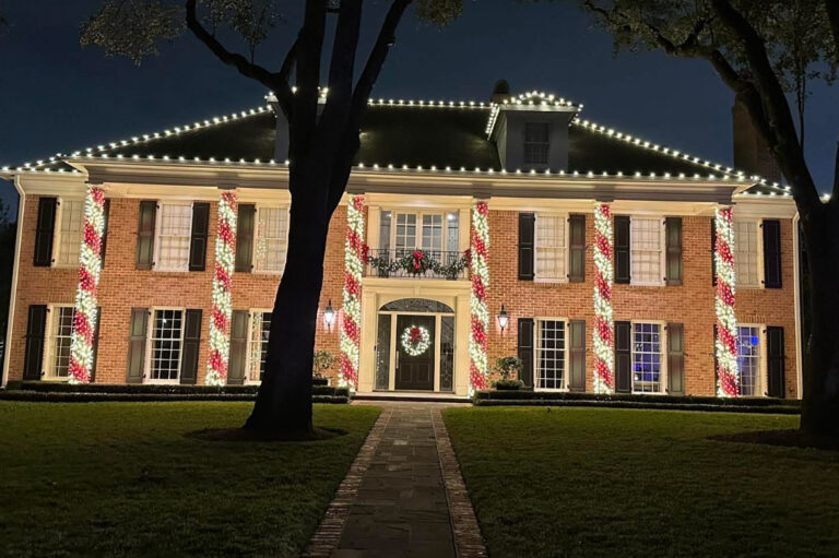 Two story brick home with roofline lighting, wreath and candy cane column wraps
