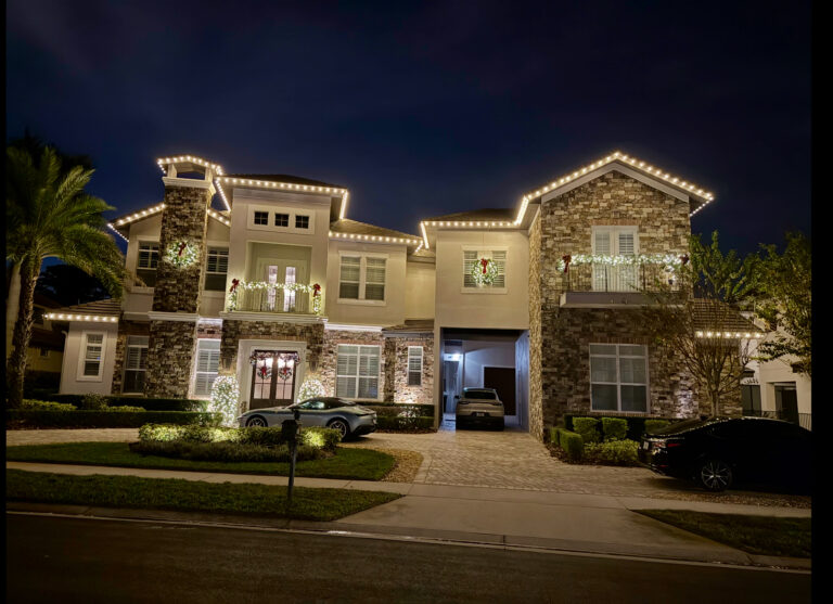 Two story stone and stucco home outlined in warm white roofline lighting