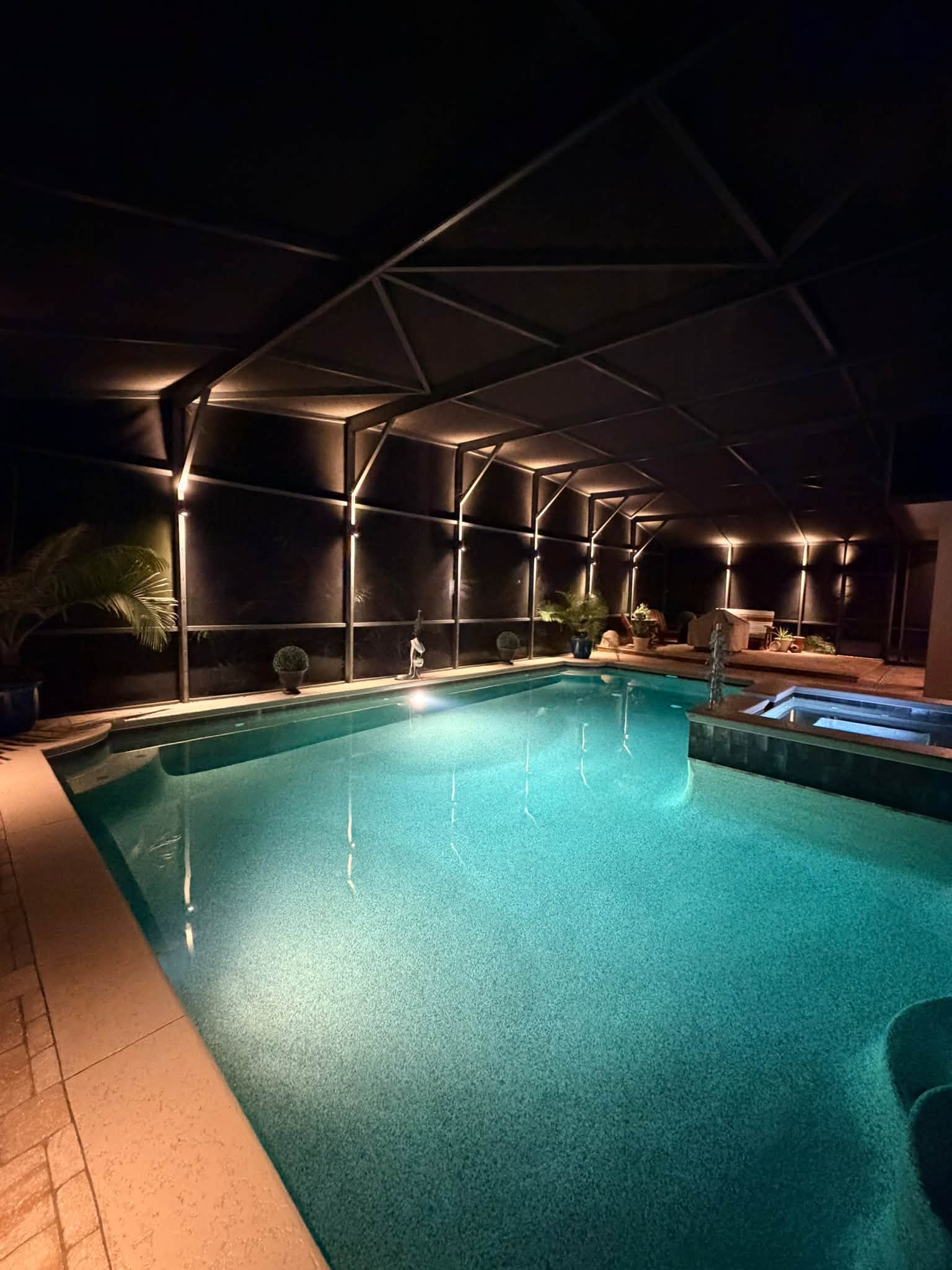 Screened pool enclosure illuminated with warm up-and-down wall sconces
