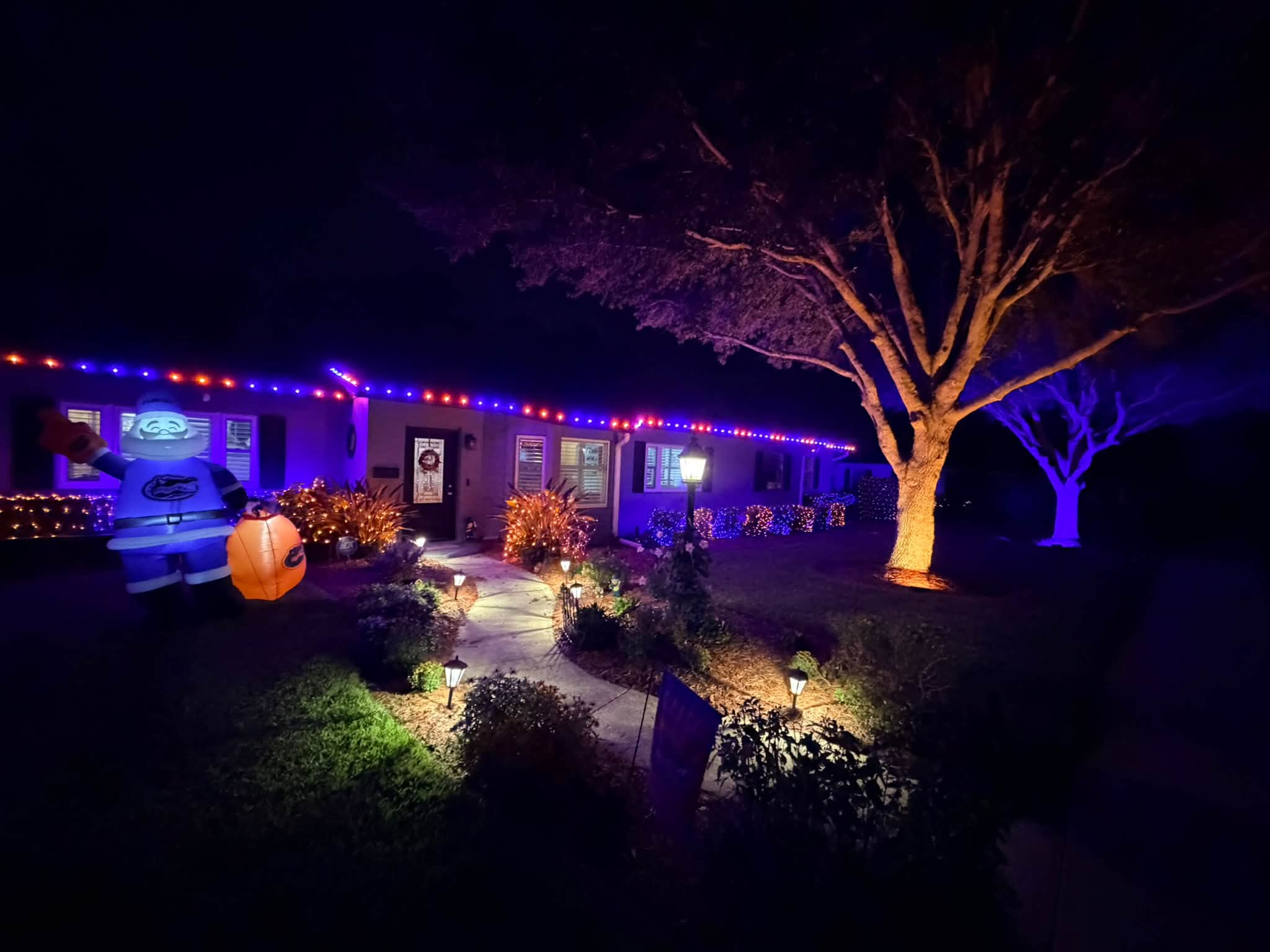 Home illuminated in orange and blue with color-changing roofline and landscape lighting
